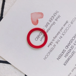 Nahaufnahme eines roten geflochtenen Rings auf minimalistischem Grußkarten-Hintergrund