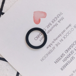 Detail eines schwarzen Silikonrings mit geflochtener Textur auf einer Präsentationskarte