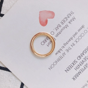 Detailansicht eines doppellagigen goldenen Rings mit gedrehter Seilstruktur auf weichem Stoff