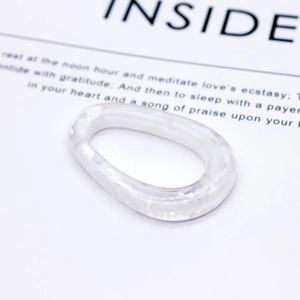 Détail d'une bague en résine marbrée blanche de forme ovale irrégulière sur fond minimaliste