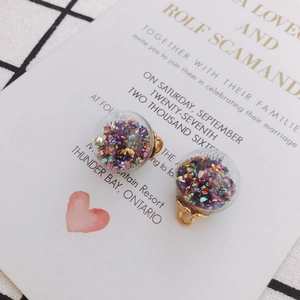 Close-up of glass orb charms with colorful sequins and golden hanging loops for DIY crafts