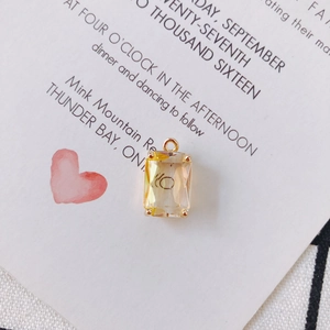 Detail of emerald-cut champagne crystal pendant with golden four-prong setting and loop