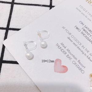Close-up of invisible U-shaped resin ear clips with pearls and gold-plated details