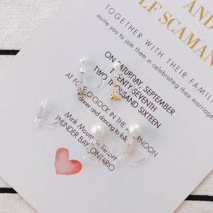 Close-up of invisible resin clip-on earrings with gold beads and pearls on a gift card