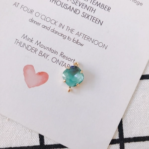 Macro view of blue-green cushion-cut crystal pendant with gold plating and double loops