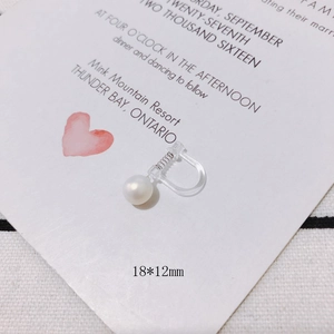 Detail of a transparent resin spring ear clip with a glossy white pearl for non-pierced ears