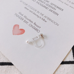 Detail of clear resin U-shaped clip-on earring converter with pearl and spring mechanism