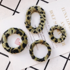 Détail d'accessoires de boucles d'oreilles en peluche léopard sur papier élégant et tissu