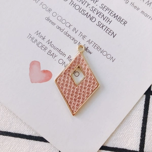 Detalle de colgante de rombo en cuero rosa con borde dorado y número 10 para pendientes DIY
