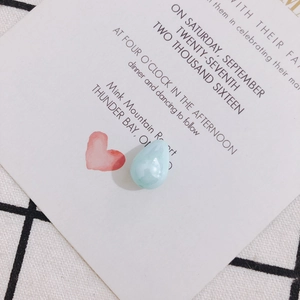 Close-up of teardrop faux pearl pendants in light blue on a decorative white card