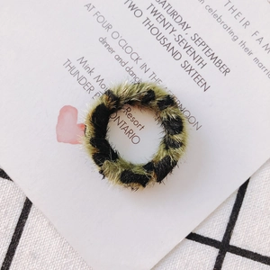 Détail macro d'un charm de boucle d'oreille léopard en peluche sur carte blanche et carreaux
