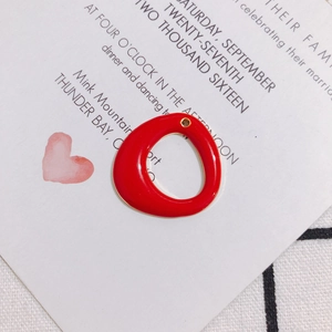 Close-up of red enamel circular charm with gold metal edge for DIY jewelry making
