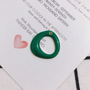 Detailed view of a green enamel round charm with gold metal edges for DIY jewelry making