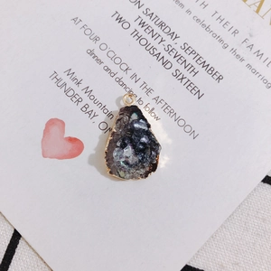 Detail of irregular teardrop resin pendant with shimmery stone texture and gold plated rim