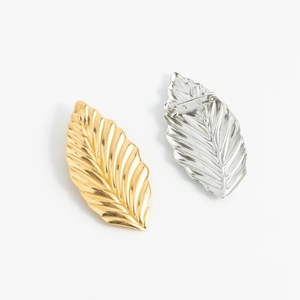 Minimalist gold and silver leaf brooches with realistic vein textures on white background