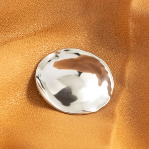 Minimalist circular lava brooch in polished silver finish on textured fabric