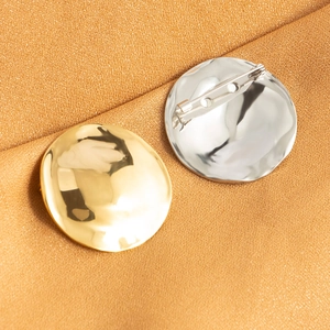 Set of gold and silver round disk brooches with irregular texture and polished finish