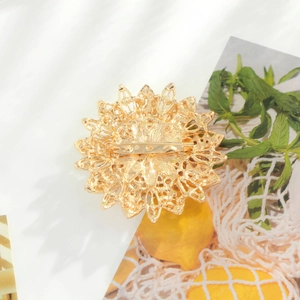 Élégante broche tournesol plaquée or avec épingle de sûreté sur fond floral décoratif