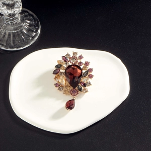 Elegant vintage brooch with large red teardrop gem and purple rhinestones in gold finish