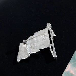 Back view of silver flag-shaped brooch with rhinestones and pin clasp mechanism