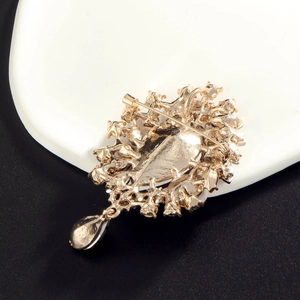 Elegant gold-plated brooch with purple gem and rhinestones featuring detailed filigree back