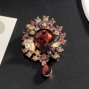 Elegant vintage gold brooch featuring deep red pear-shaped gems and purple rhinestones