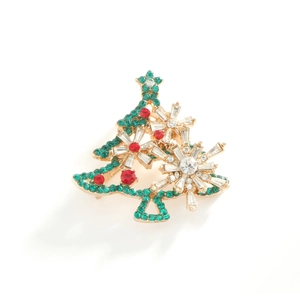 Golden Christmas tree brooch with sparkling green and red rhinestones on white background