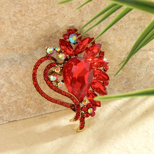 Elegant gold heart flower brooch with red crystal teardrop and rhinestones on stone background