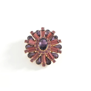 Elegant floral round brooch with purple crystals and gold alloy base on white background