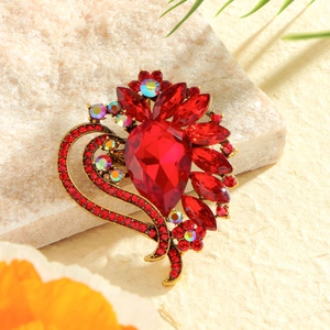 Vintage gold heart brooch with red crystals and rhinestones on stone background