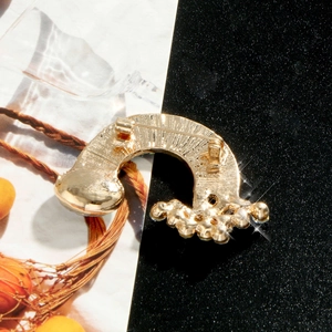 Back view of a gold curved rainbow brooch with pin closure and sparkling rhinestones