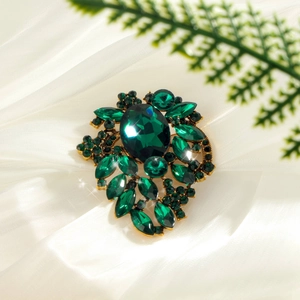 Elegant gold leaf brooch with large emerald green oval gemstone and marquise rhinestones