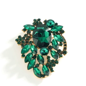 Elegant leaf-shaped gold brooch with large green crystal and sparkling rhinestones