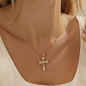 Elegant gold cross pendant necklace on model with a delicate sparkling link chain