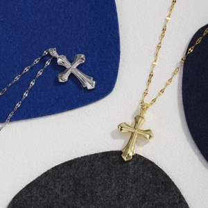 Minimalist gold and silver cross necklaces with embossed design on textured background