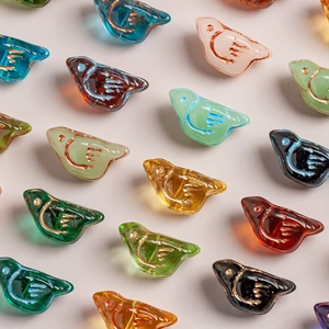 Detailed macro view of colorful Czech glass bird beads with vintage gold-lined wings and eyes