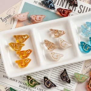 Macro shot of colorful bird-shaped Czech glass beads with golden outlines for DIY jewelry