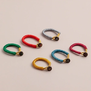 Detailed top view of six colorful handmade braided Vajra knot rings with gold accents