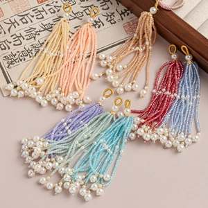 Détail de pompons en perles colorées avec perles et anneaux dorés pour la création de bijoux