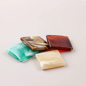 Close-up of square resin beads with marble texture in mint, amber, and cream tones