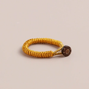 Close-up of golden handmade braided knot ring with a dark brown button fastener