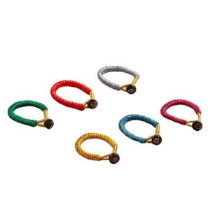 Handmade woven cord rings in six colors with decorative round beads on white background