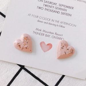 Pink heart resin stud earrings with gold glitter flakes on a white card display