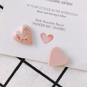 Pink heart-shaped resin earrings on checkered tablecloth for DIY jewelry design