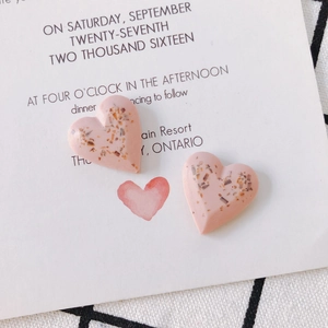 Pink heart resin earrings with gold leaf flakes on a decorative white card background
