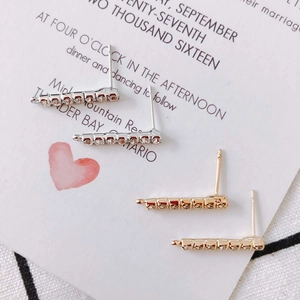 Macro shot of vertical row-set diamond stud earrings in silver and gold plating