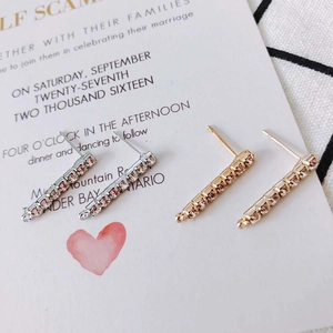 Silver and gold bar stud earrings with sparkling crystals on a wedding invitation card