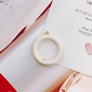 Detail eines runden cremefarbenen Harzanhängers mit goldener Öse für DIY-Schmuck