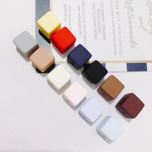 Vista macro de 12 cuentas de silicona cuadradas de colores con agujeros para joyería DIY