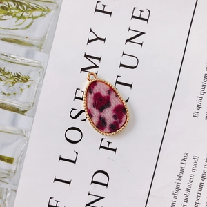 Detail van ovale hanger met roze luipaardprint en gouden kralenrand voor DIY sieraden